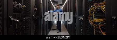 Adult Caucasian Man Managing Server Equipment in Modern Data Center Stock Photo