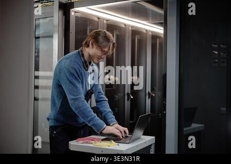 Middle Aged Caucasian Man Working on Laptop in Modern Server Room Stock Photo