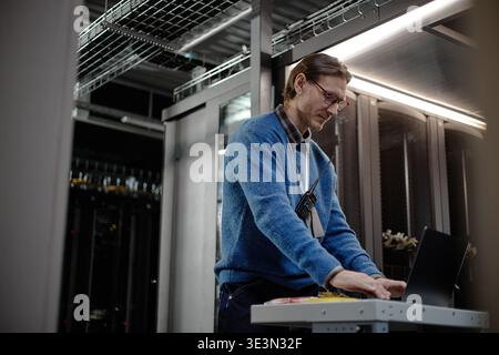 Middle Aged Caucasian Man Working on Laptop in Data Center Server Room Stock Photo