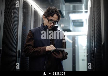 Young Adult Asian Man Using Digital Tablet in Data Center Corridor Stock Photo