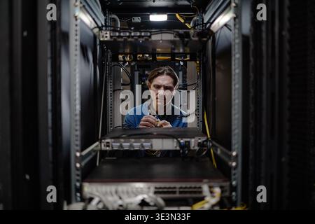 Caucasian Middle Aged Man Repairing Server Equipment in Data Center Rack Stock Photo