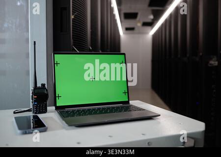 Laptop with Green Screen Displaying in Data Center Server Room Environment Stock Photo