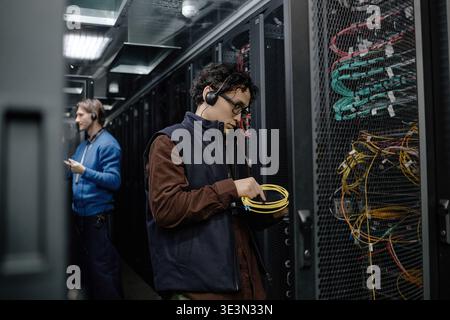 Young Adult Man Installing Network Cables in Server Room Stock Photo