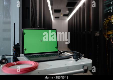 Laptop with Green Screen Displaying in Modern Data Center Server Room Stock Photo
