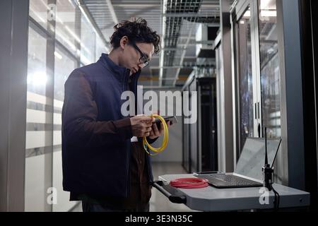 Young Adult Asian Man Configuring Network Cables in Data Center Stock Photo