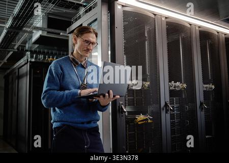 Caucasian Young Adult Man Using Laptop While Working Inside Data Center Stock Photo