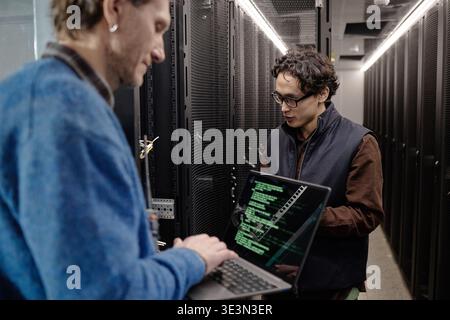 Men Collaborating with Laptop in Data Center Server Room Stock Photo