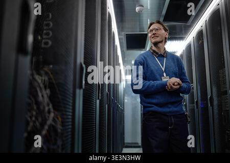 Middle Aged Caucasian Man Standing in Data Center Corridor and Smiling Stock Photo