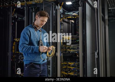 Middle Aged Caucasian Man Inspecting Network Cables in Server Room Stock Photo