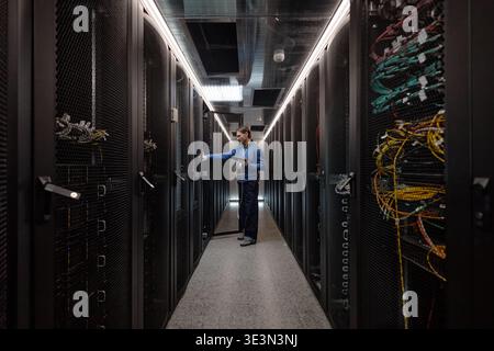 Adult Caucasian Man Managing Network Cables in Data Center Server Room Stock Photo
