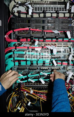 Unrecognizable Man Configuring Network Cables in Data Center Server Rack Stock Photo