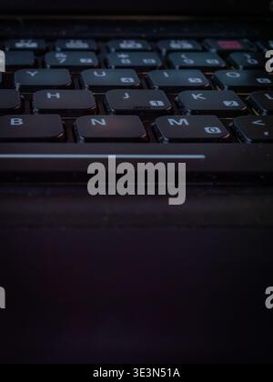 Macro high-angle view of a black laptop keyboard with white lettering and low-profile chiclet keys in soft indoor lighting Stock Photo