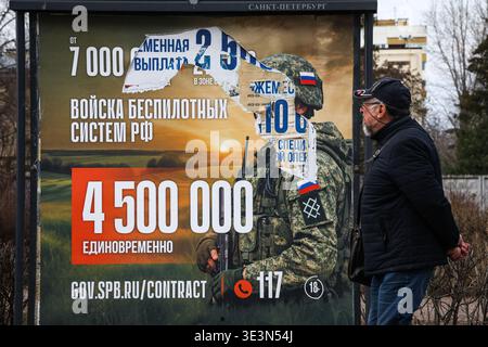 A man walks past an information billboard advertising contract service in the Russian Armed Forces, installed on one of the city streets. A large-scale information campaign to recruit citizens for contract military service continues on the streets of St. Petersburg. Billboards and billboards throughout the city display up-to-date information on recruitment for various units of the Russian Armed Forces. Outdoor advertising places particular emphasis on financial terms: billboards list the one-time payment amounts, which will reach 4,500,000 rubles in March 2026. Campaign materials also include Stock Photo