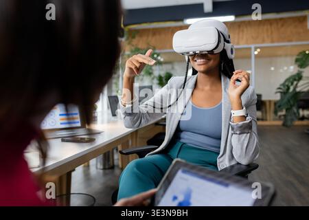White VR headset delivering virtual demo while tablet displaying charts on office desk Stock Photo