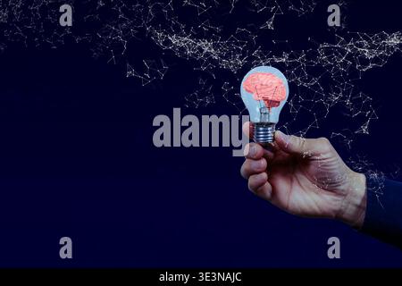 Close-up of a hand holding a light bulb with brain illustration and neural network on dark blue background, symbolizing artificial intelligence, creat Stock Photo