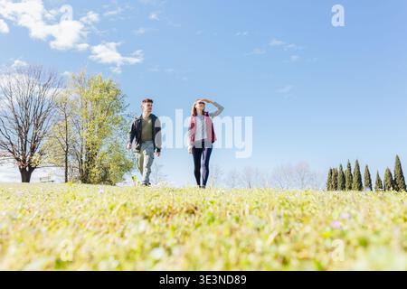 full length view of a man and a woman walking in the park on a sunny day Stock Photo
