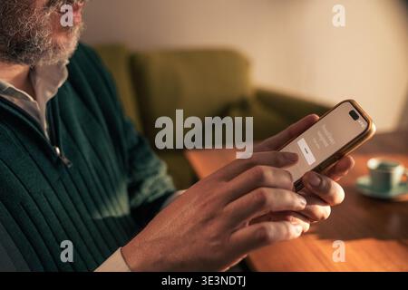 Mature man using smartphone with personal finance mobile application at home, checking budgeting, banking and retirement planning on digital financial Stock Photo