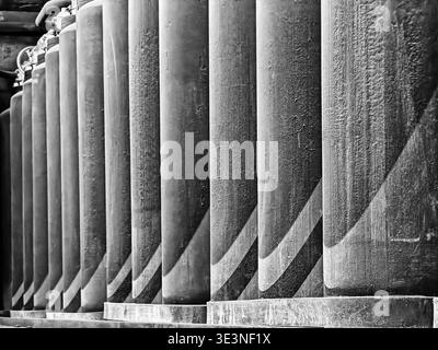 A series of equipment in a mothballed power plant creates a repetitive series in a row along a wall. In black and white. Stock Photo