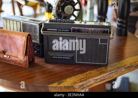 Vintage leather handbag with retro radio equipment displayed on table in cafe interior, March 10, 2026, Alanya, Turkey Stock Photo