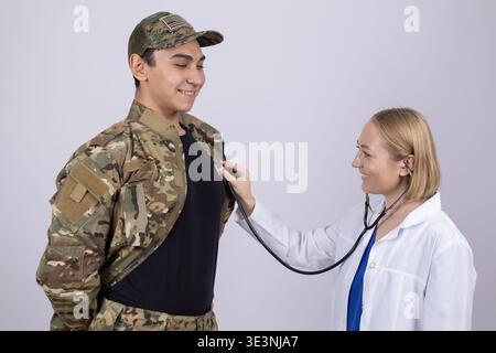 Female doctor listening to a soldier's chest in studio Stock Photo