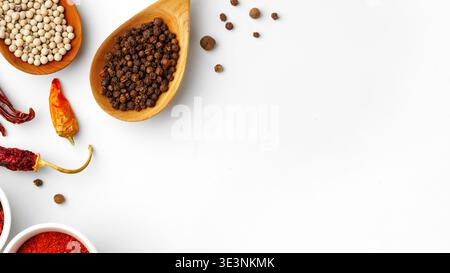 Spice assortment on a white surface with wooden bowls and various spices spread around Stock Photo