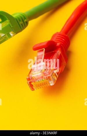 Red and green ethernet cables lie on a bright yellow background Stock Photo