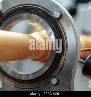 Close-up view of a metal bearing and wooden rod during a woodworking process Stock Photo