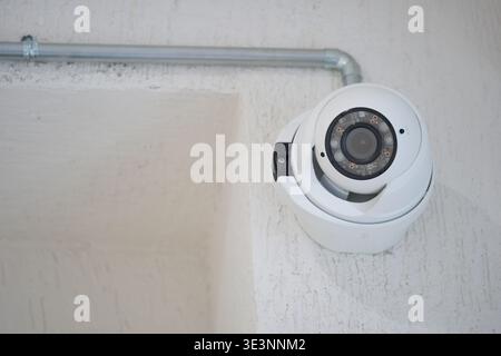Security camera mounted on wall in indoor space Stock Photo