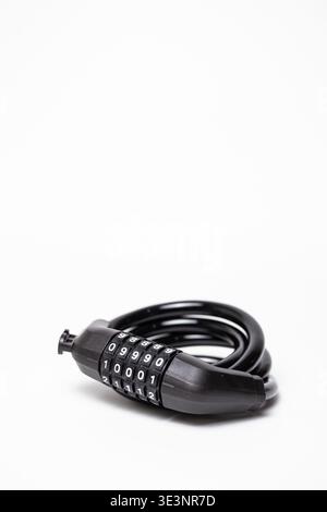 Close-up of a sturdy black combination bike lock with coiled flexible cable and numbered code wheels, neatly arranged on a clean white background. Stock Photo