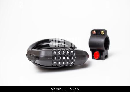 Studio product shot of a sturdy black combination bike lock with coiled cable and separate mounting bracket with red quick-release button. Stock Photo