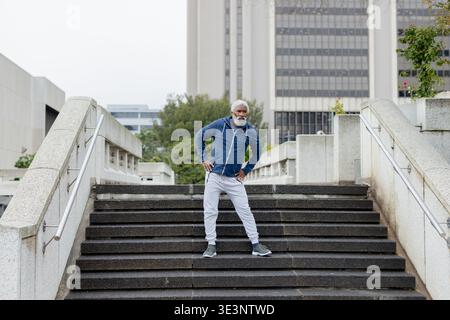 African american man standing on stairs in urban plaza wearing fitness attire Stock Photo