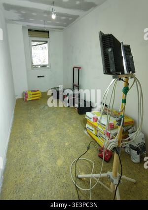 Wide-angle shot of a room undergoing a complete renovation in Barcelona, featuring essential construction tools, materials including Weber plaster bag Stock Photo