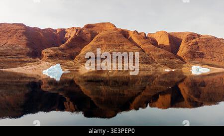 Small icebergs drifting in front of ochre mountains, Rodepynten, northeastern Greenland. Stock Photo