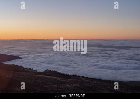 Sunrise above clouds in Teide National Park Tenerife Spain with sun rays over volcanic mountain ridge scenic landscape Stock Photo