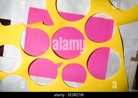 A vibrant abstract layout featuring layered yellow, pink, and white paper scraps from an art project. The composition showcases a complex arrangement Stock Photo