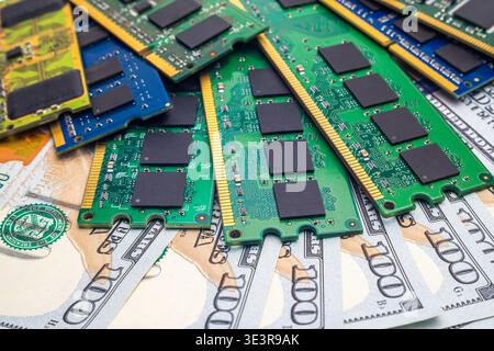 Various computer memory sticks are laid on top of multiple one hundred dollar bills in this setting, showing technology and money together. Stock Photo