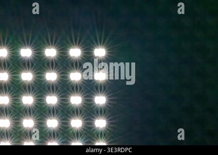 A grid of bright white LED lights shining against a dark background creating a starburst effect and geometric pattern Stock Photo