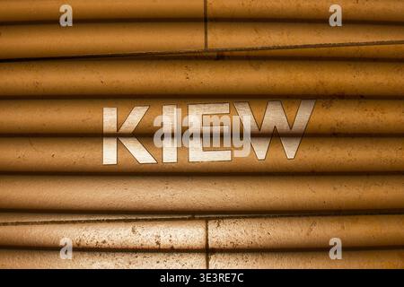 Metallic letters spelling Kiev on a textured surface with horizontal shadow lines creating a pattern of light and dark stripes. Stock Photo