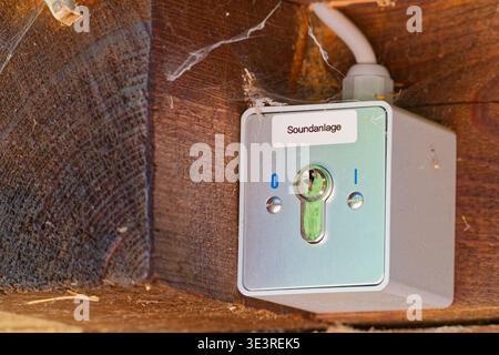 An old electrical switch box labeled sound system mounted on a wooden surface with visible cobwebs and dust in a rustic setting. Stock Photo