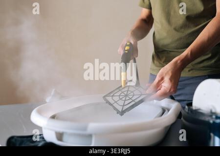Cropped shot of housewife using steam cleaner to clean air humidifier filter in basin at home, ensuring regular maintenance for maintaining healthy Stock Photo