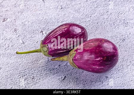 Fresh, raw striped eggplants on a rustic background. This still life highlights the vibrant purple white colors of the vegetables. Ideal for healthy e Stock Photo