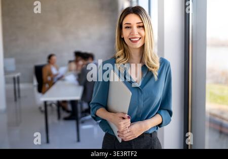 Young happy successful business woman working in corporate office Stock Photo