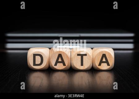 DATA word on wooden blocks with reflection and blurred laptops background. Big data, analytics, cloud computing and IT infrastructure concept. Stock Photo