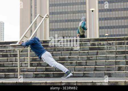 Senior african american man doing inclined push-ups on metal handrail at plaza stairs Stock Photo