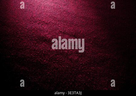 Macro shot of deep red textile material showing detailed weave pattern and subtle highlight with dark shadow for an elegant and moody background. Stock Photo