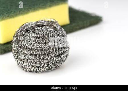 Close-up studio shot of a stainless steel wire wool scrubber ball with a yellow and green kitchen sponge and green abrasive scrubbing pad arranged on Stock Photo