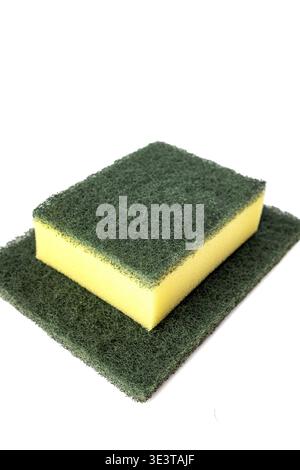 Close-up product shot of a yellow cellulose foam kitchen sponge bonded with a dark green abrasive scrubbing pad, placed on top of a larger flat scouri Stock Photo