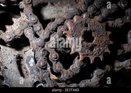Macro shot of rusted iron sprockets and greasy chains covered in dirt and oil, showcasing industrial decay and mechanical wear with dark lighting. Stock Photo