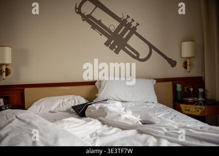 Unmade hotel bed with notebook computer on top Stock Photo