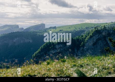 Scenic mountain cliffs and green hills under cloudy sky, dramatic nature landscape Stock Photo